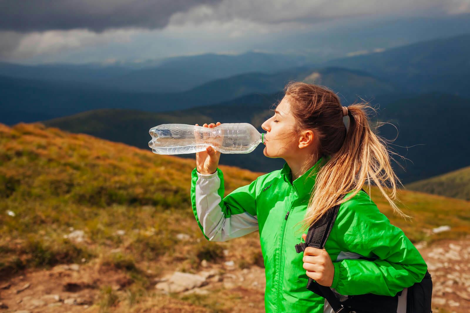 How long does it take to recover from dehydration: woman drinking water while hiking