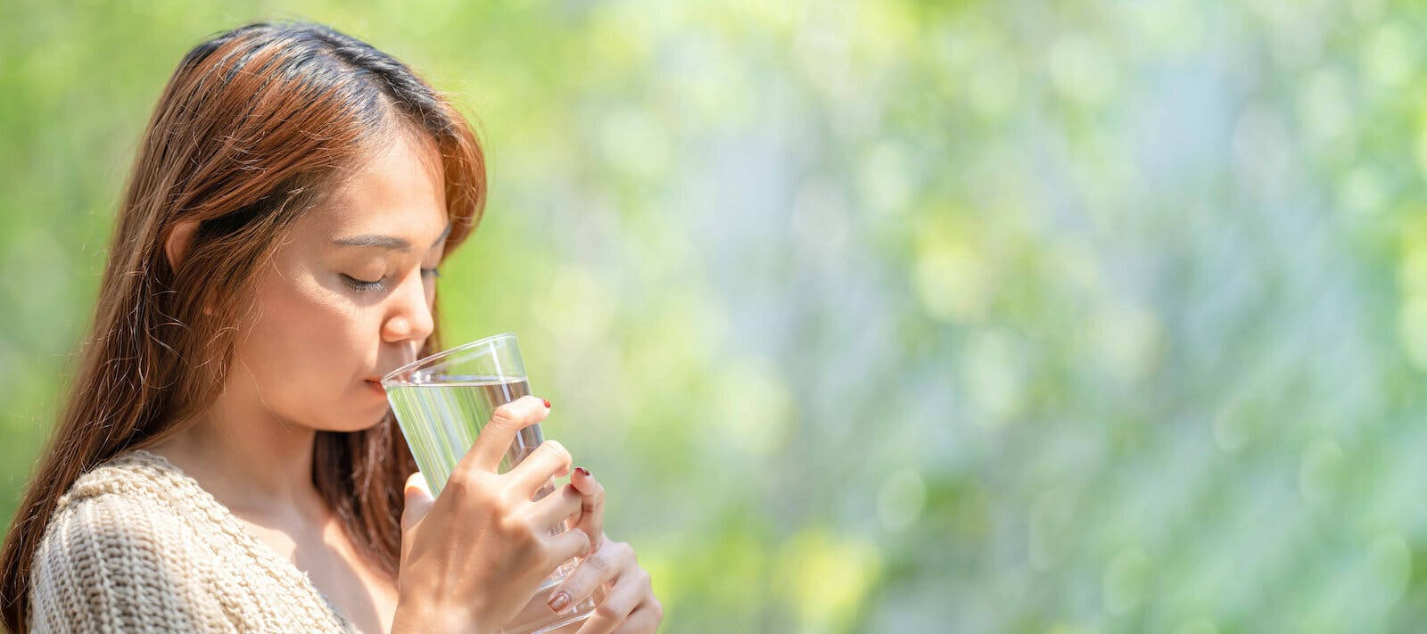 Not drinking enough water: woman drinking a glass of water